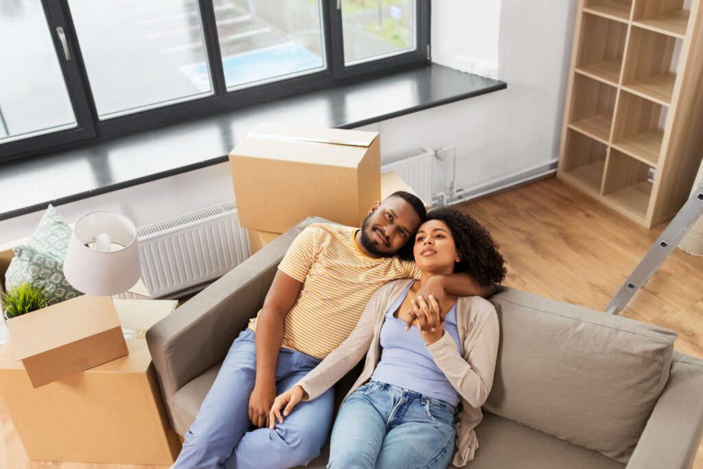 Secure a new beginning with confidence! This happy couple, in Las Vegas, enjoys their first moments in their new home, surrounded by boxes, a testament to the peace of mind that comes from a well-prepared mortgage application.