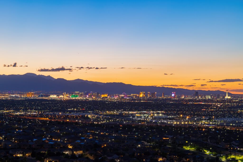 High-angle night view of Henderson cityscape with the Las Vegas Strip skyline in the distance.