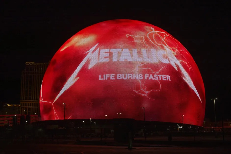 The exterior LED Exosphere of the Las Vegas Sphere illuminated in vibrant red and white displaying the Metallica logo, lightning bolts, and the text Life Burns Faster.